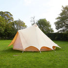 Beige bell tent on grass with trees in the background