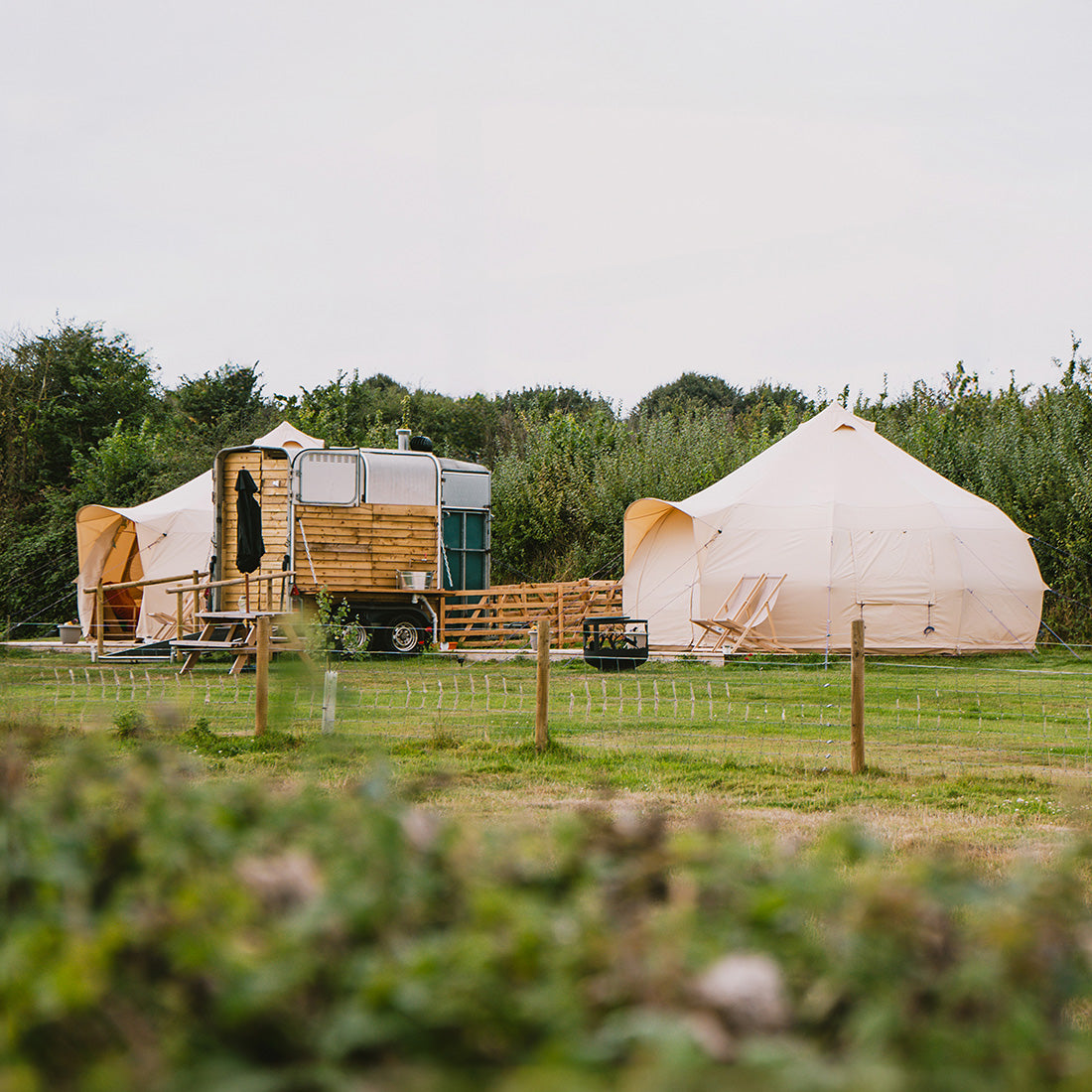 two boutique camping 5m luna bell tents in a field with toilet shack
