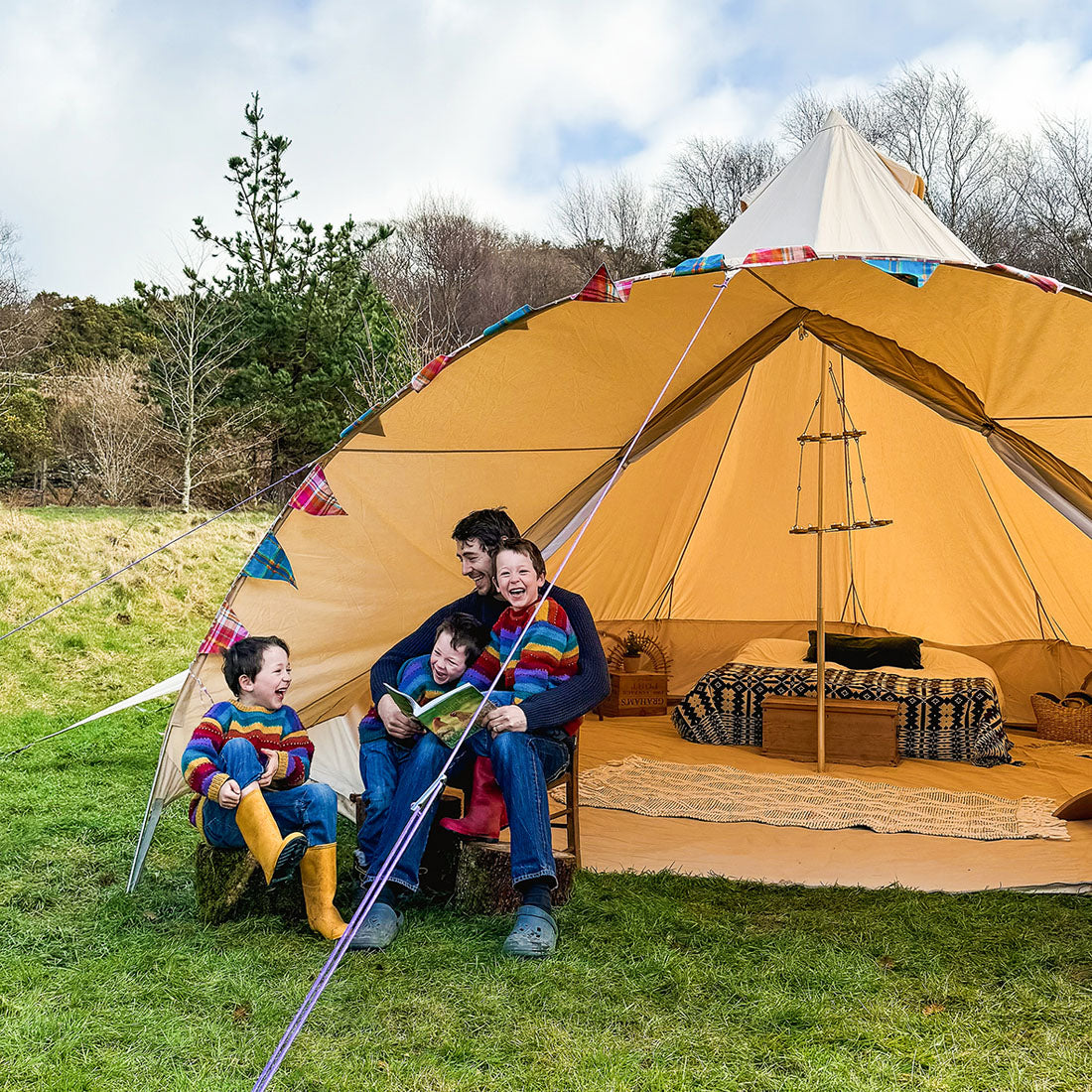 boutique camping star bell tent in a field with a family of triplets and their dad
