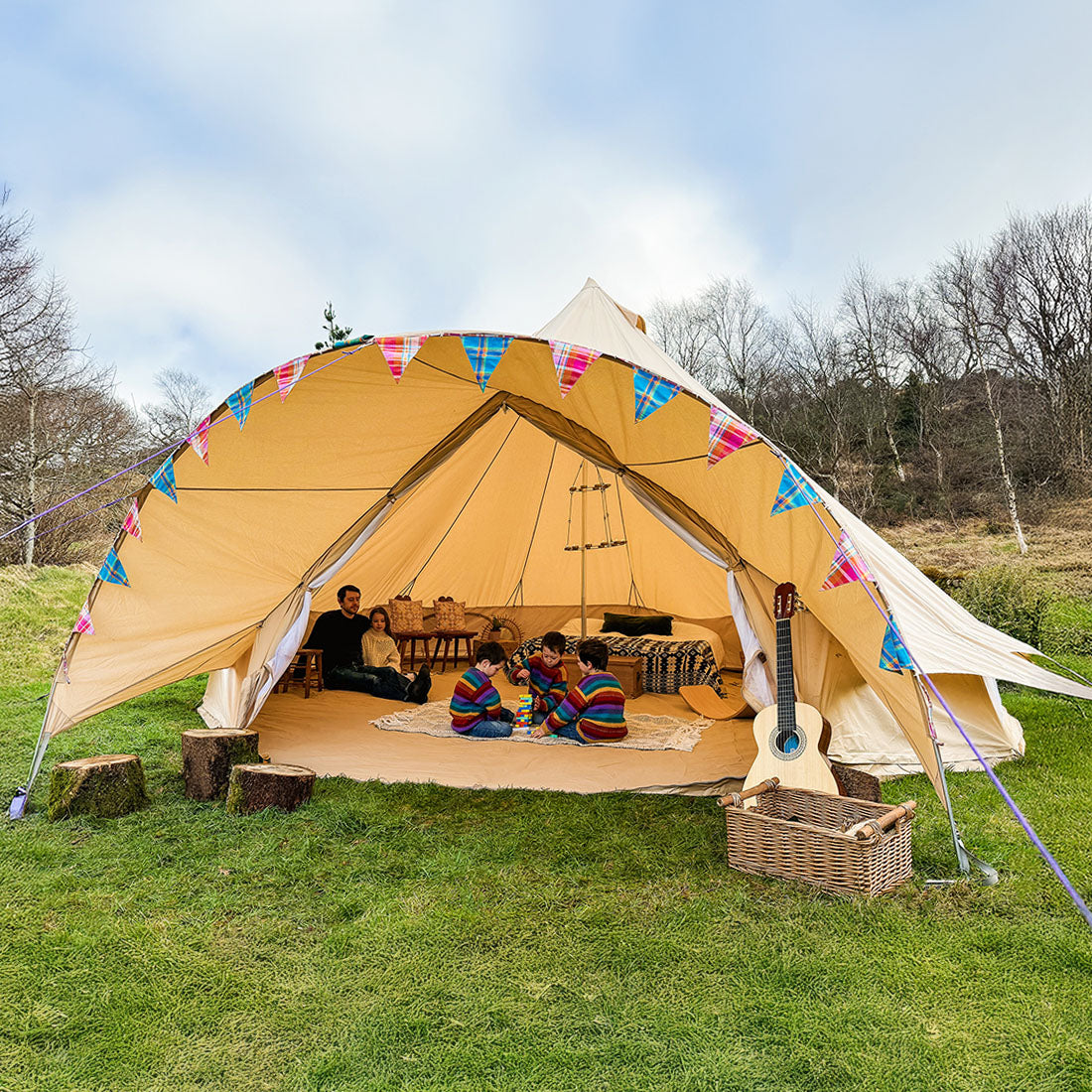sandstone boutique camping 6m star bell tent with children playing inside featuring bunting and a chandelier