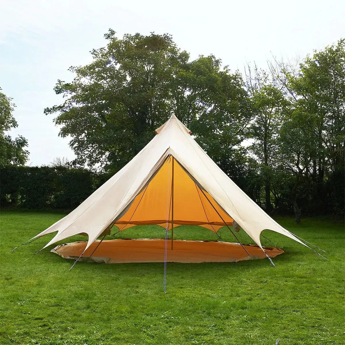 Bell tent with orange interior on a grassy area with trees in the background and the sides lifted up