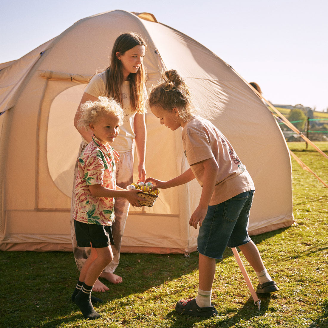 children sharing easter eggs in front of the boutique camping nova inflatable air tent