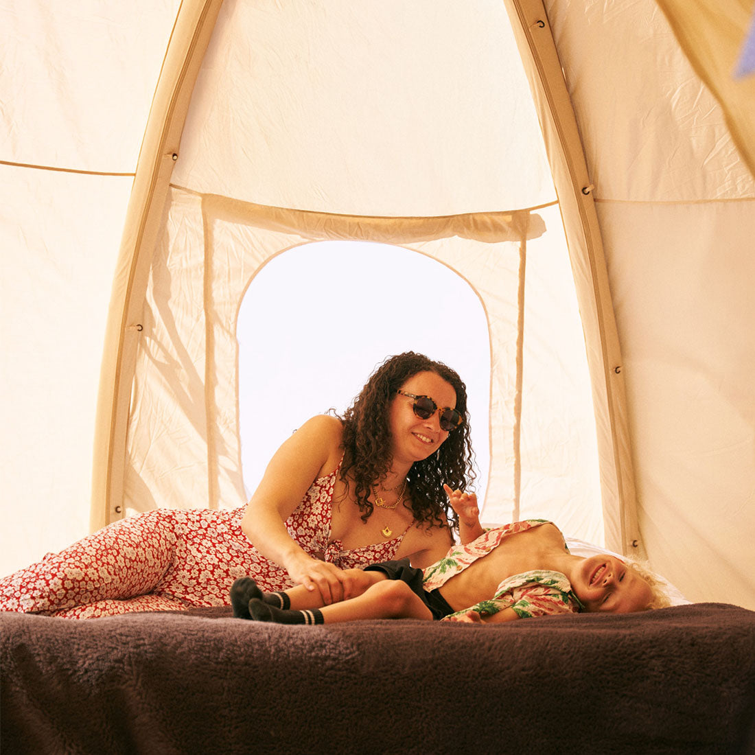 mum and son laughing on a bed inside the nova air dome tent