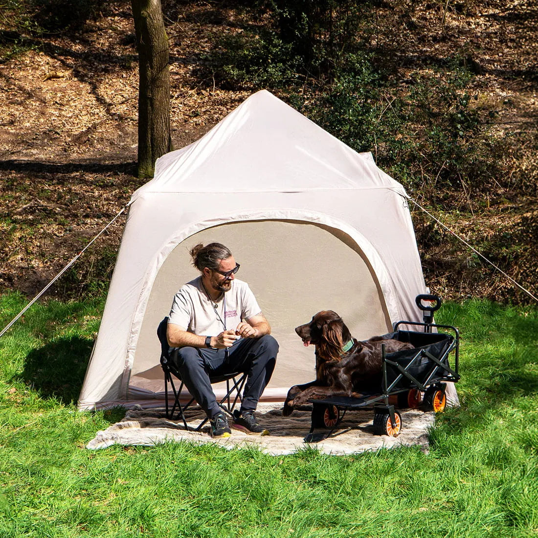 man and dog sat outside the stellar festival tent with green grass and bright sun