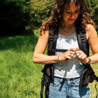 girl clipping up chest straps of boutique camping bell tent backpack