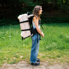 girl smiling carrying a boutique camping tent on a boutique camping backpack
