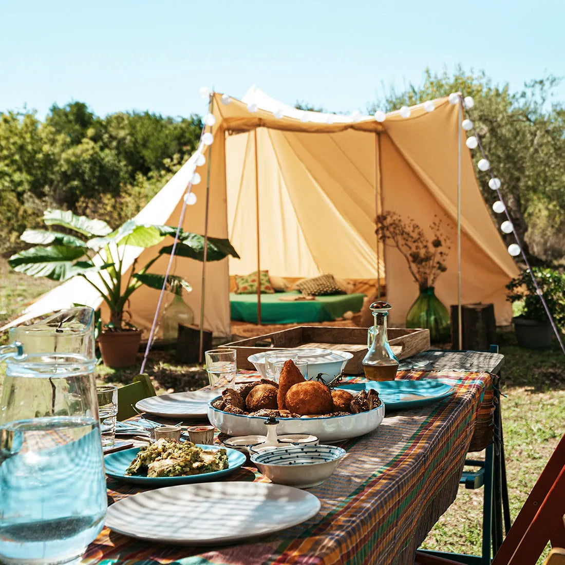 a table of sicilian food in the foreground with the tucana tent slightly out of focus in the background