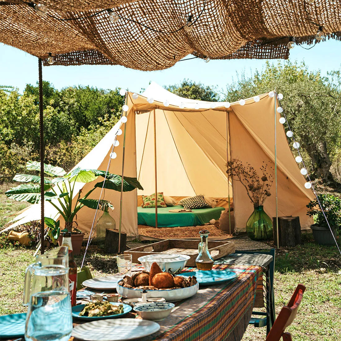 front view of the tucana tent with the front door open, the foreground features a table of sicilian food under a rattan canopy