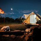the tucana tent under a night sky featuring a dog laying down in the foreground infront of some cobbled steps with the moon in the background