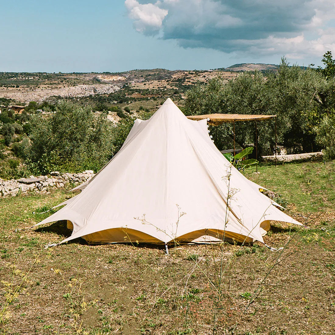 back view of the tucana tent situated on grass with trees and a blue sky