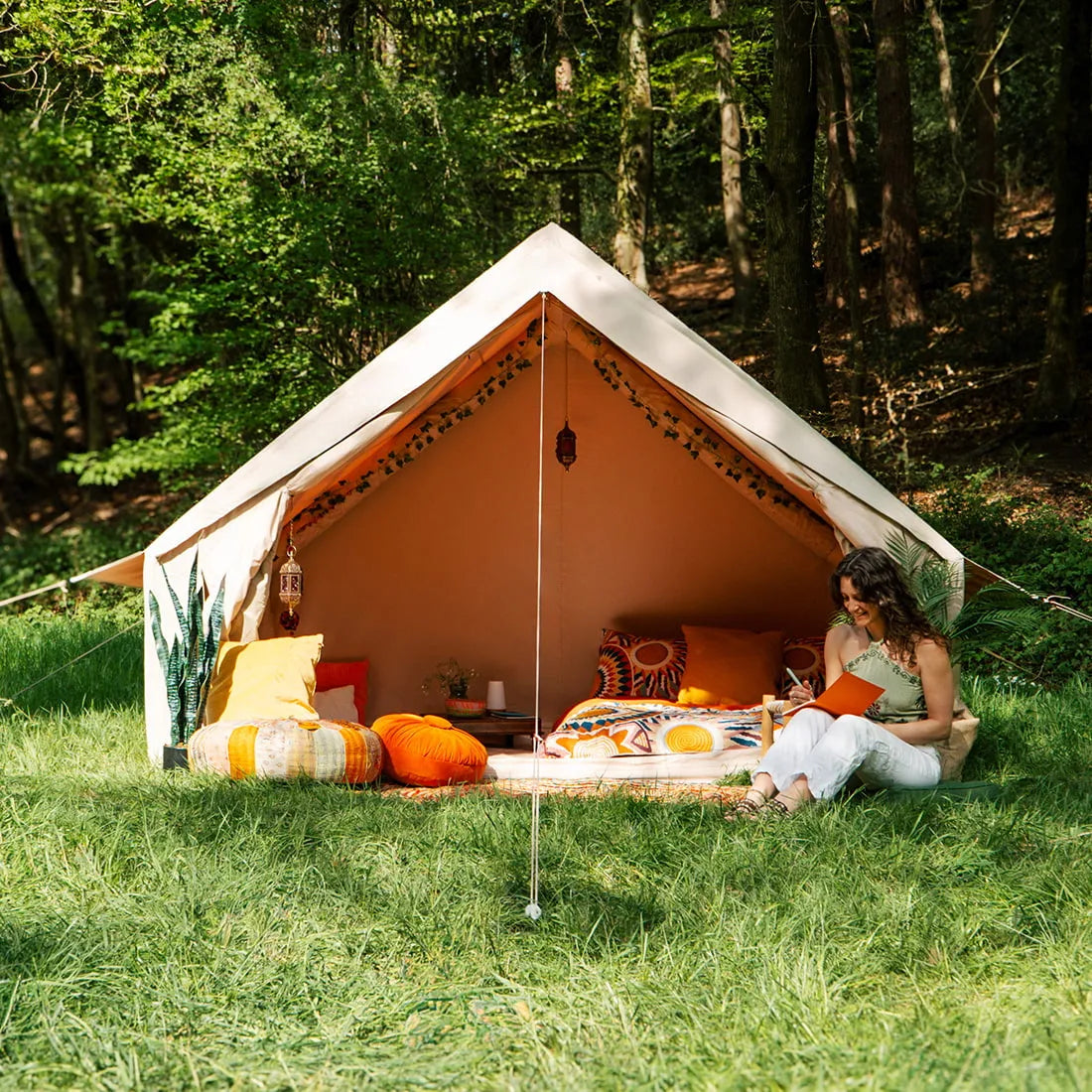 Spacious Vela Air Tent with bright orange cushions and natural wood accents – Perfect glamping setup from Boutique Camping