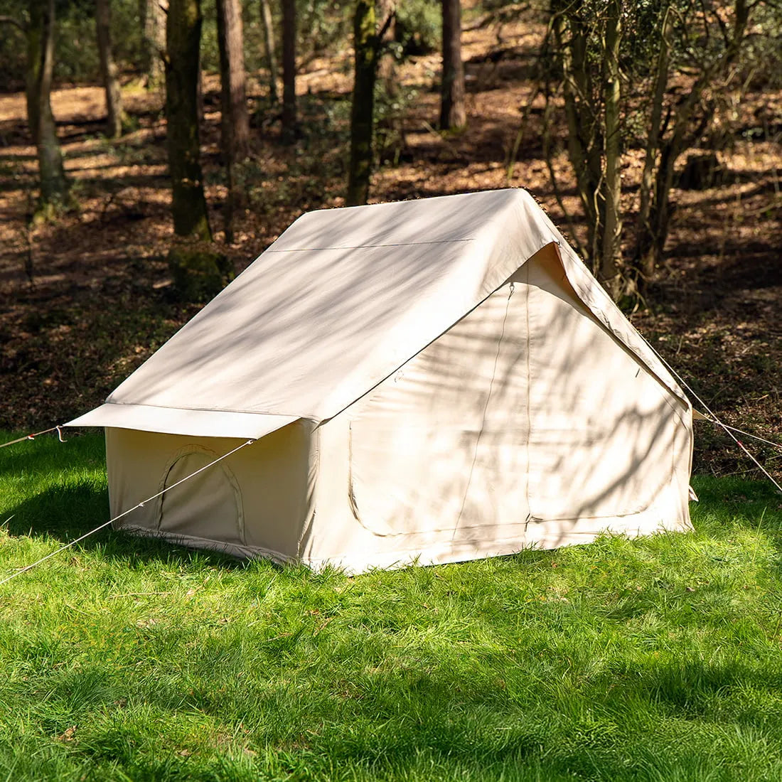 Vela Air Tent pitched solo in a peaceful woodland area, surrounded by trees and dappled sunlight.