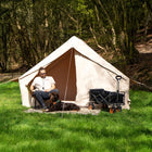 Vela Air Tent fully set up on a bright grassy field, featuring its wide doorway and durable beige fabric.