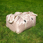 Rolled-up and packed Vela Air Tent in a secure carry bag, resting on lush green grass.