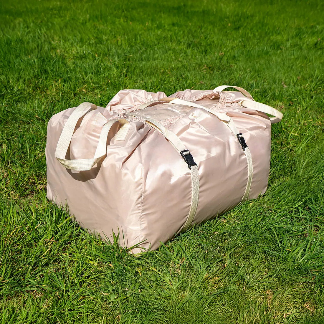 Rolled-up and packed Vela Air Tent in a secure carry bag, resting on lush green grass.