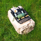 Vela Air Tent packed tightly in a beige carry bag with an air pump placed on top, set on green grass.
