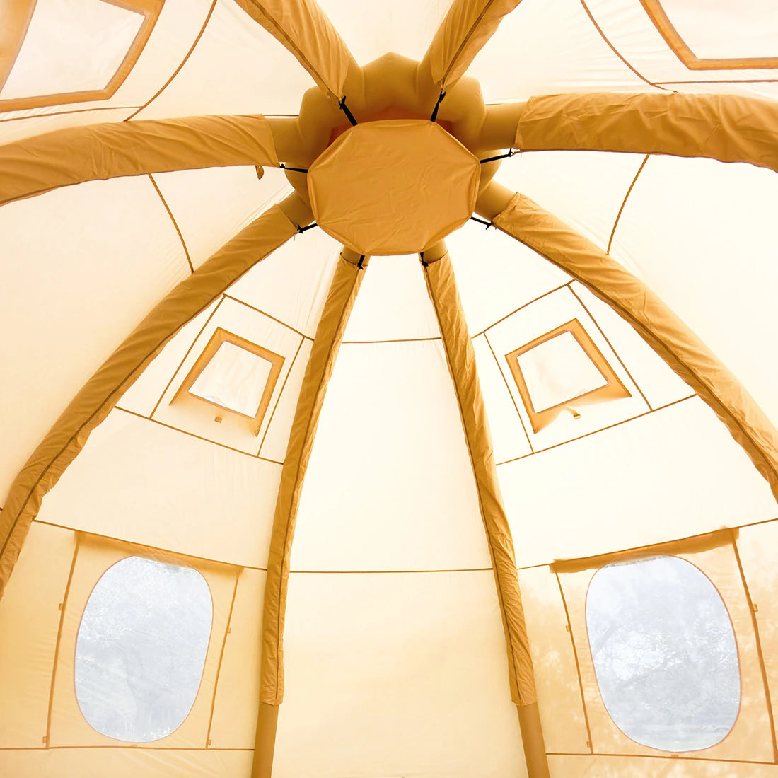 The interior of a boutique camping nova air dome glamping tent, showing the radial support poles and circular window cutouts.