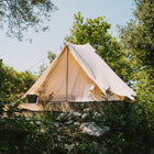 boutique camping bell tent plus 4m tent with netting door closed and trees and plants in the foreground and background