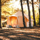 side view of a 4m polycotton boutique camping luna bell tent surrounded by trees at sunset 