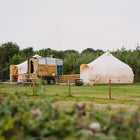 two boutique camping 5m luna bell tents in a field with toilet shack