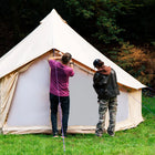 two people setting up the 5m bell tent pro in a forest setting
