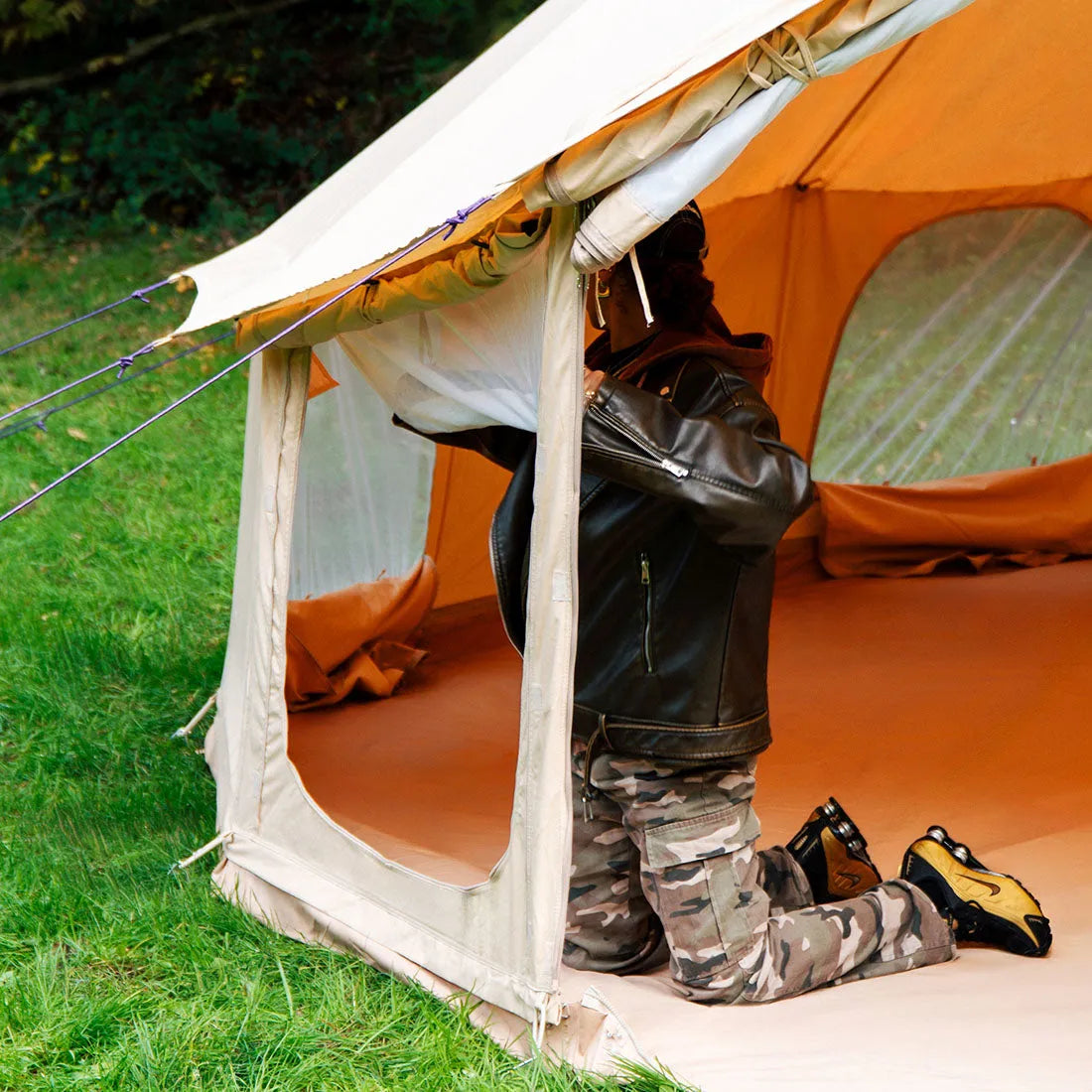 person rolling up mesh side windows of boutique camping's 5m Bell Tent Pro tent