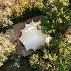 boutique camping bell tent plus aerial view on a platform within a group of trees in the sun 