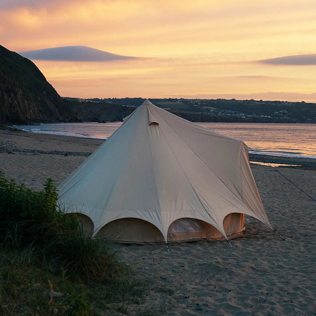 bell tent plus glamping tent on a sandy beach with a sunset sky
