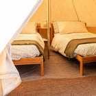 Two wooden beds inside a boutique camping bell tent plus glamping tent with patterned bedding and pillows.