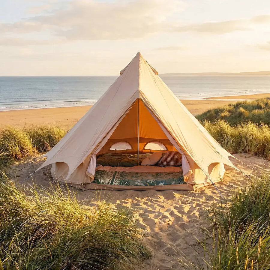boutique camping bell tent plus 3m glamping tent forward facing with doors open and bedding inside on a beach at sunset 