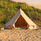 boutique camping bell tent plus on a sandy beach with grassy hill in the background