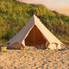 boutique camping bell tent plus on a sandy beach with grassy hill in the background