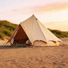 bell tent plus on a sandy beach with a sunset in the background