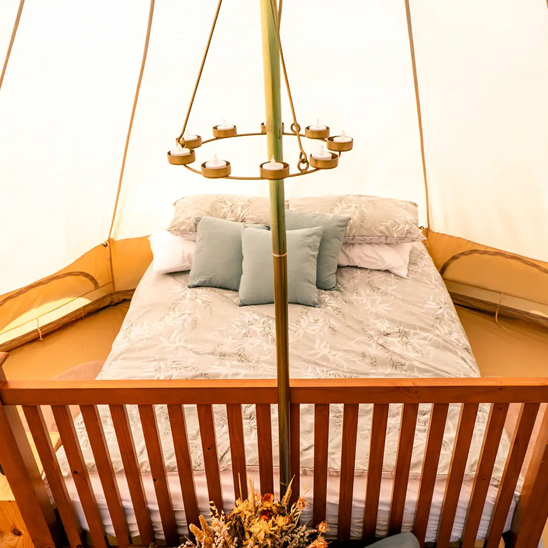 Bed with pillows and a decorative stand in a cozy boutique camping glamping tent