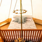 Bed with pillows and a decorative stand in a cozy boutique camping glamping tent