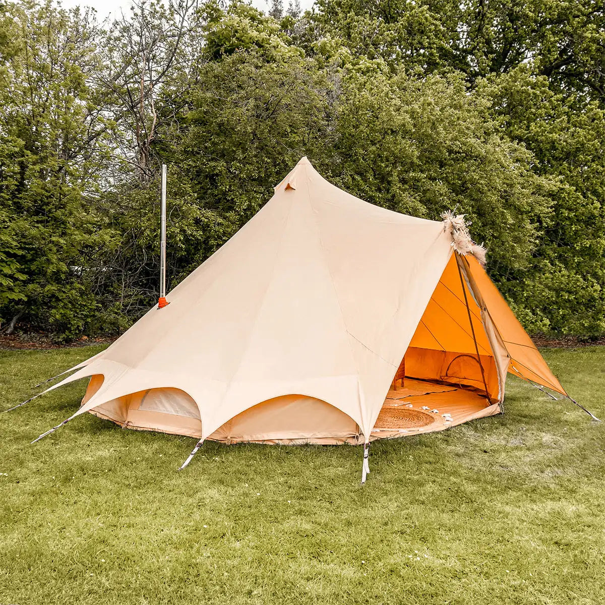 boutique camping bell tent plus fire retardant with stove flue side view in grassy field