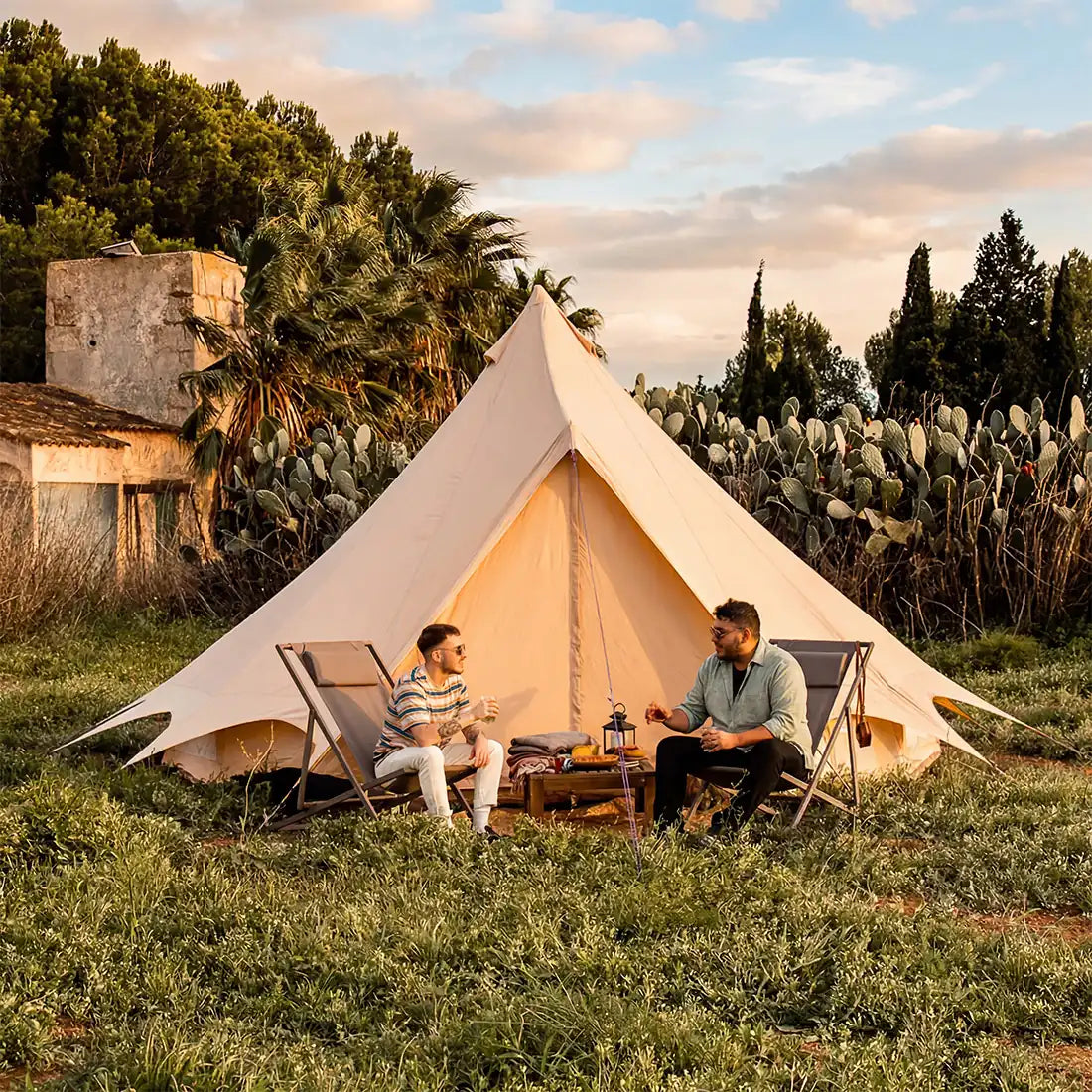 Bell tent plus glamping tent exterior setup in tropical field