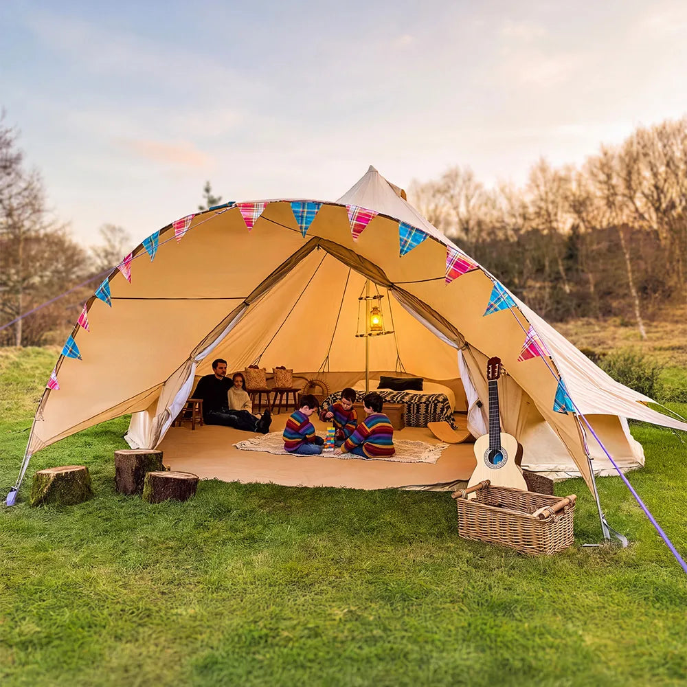 boutique camping star bell tent pitched on grass with bunting and gutiar and kids playing in tent with dad