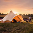 boutique camping star bell tent pitched on grass lavender field with stove outside and man on bike