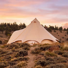 boutique camping star bell tent pitched on grass with mountain scenery