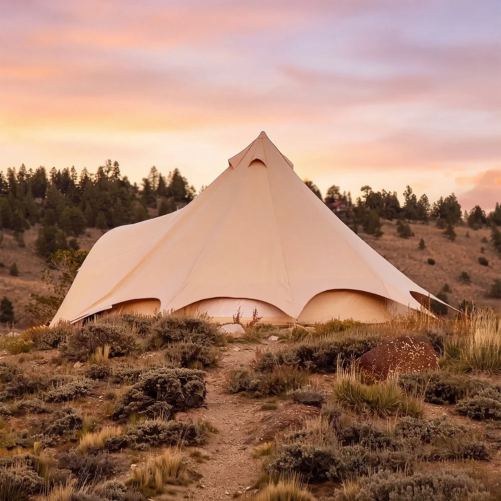 boutique camping star bell tent pitched on grass with mountain scenery