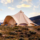 boutique camping star bell tent pitched on grassy hill with mountains in back