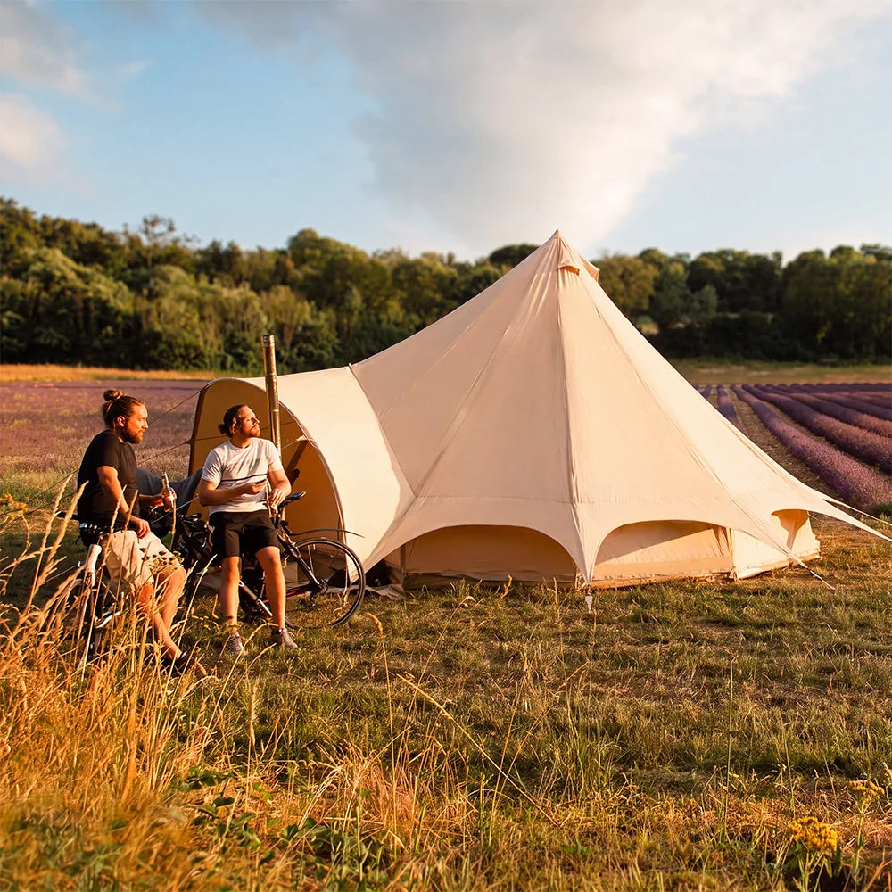 two men outside boutique camping star bell tent in lavender field on bikes enjoying a bottle of beer