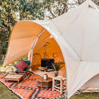boutique camping star bell tent pitched on grass with stove inside and rugs