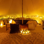 boutique camping bell tent interior with bamboo pole and cosy soft furnishings