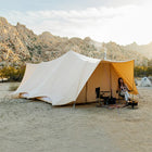 woman sitting in front of a tucana double door tent in a desert landscape with mountains in the background 