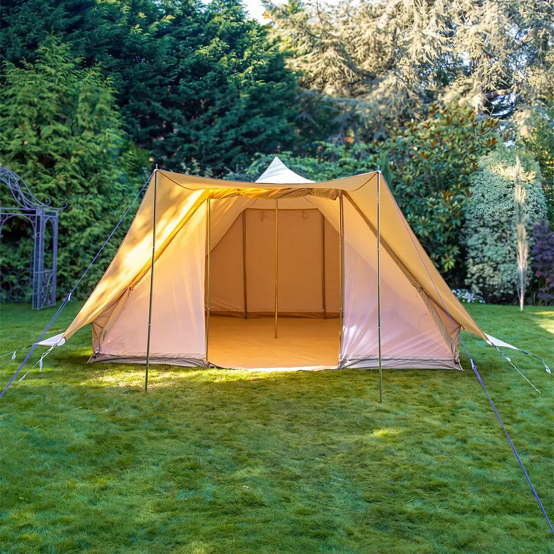 boutique camping tucana tent with door open set up on a grassy area with trees in the background 