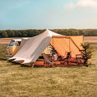 Camper van with a double door tucana tent and glamping furniture in a field