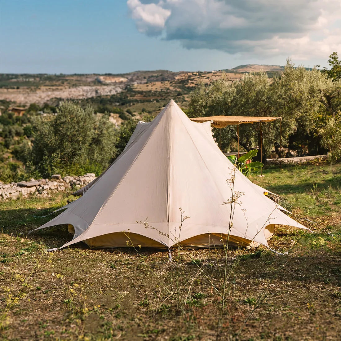 tucana bell tent rear view in a natural landscape with trees and open blue sky with clouds 