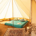 inside view of boutique camping tucana tent with a double bed, pillows, and decorative items with matting and rug